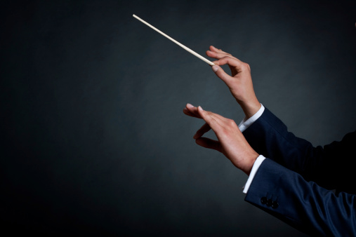 image of a male orchestra conductor directing with his baton in concert