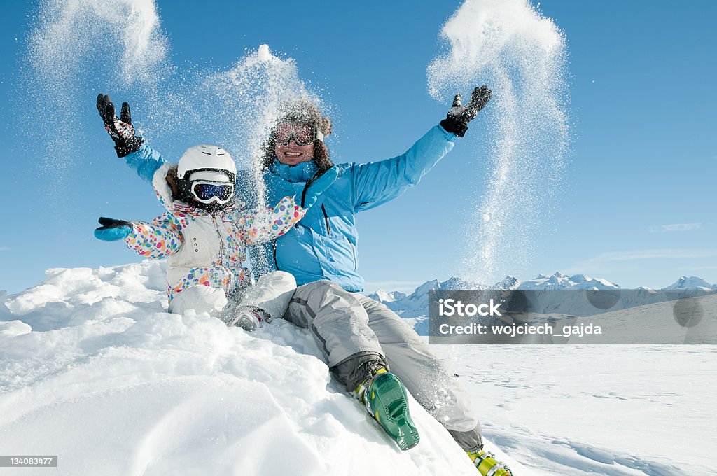 Child and adult happily playing in snow in full winter gear Father and daughter having fun on ski holiday Apres-Ski Stock Photo