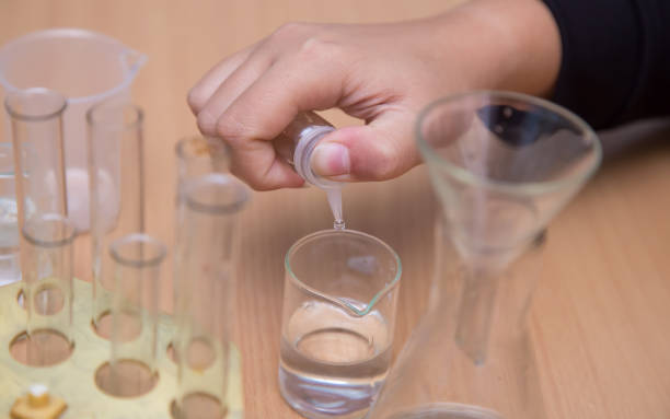 istock Close-up of a student's hand dripping a chemical solution into a glass. 1340835589