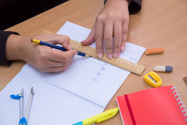 istock Close-up hands of a student work with a pencil in a notebook. 1340836095