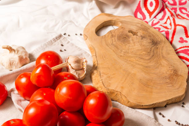 istock Cutting board made of olive tree, next to a bunch of tomatoes, garlic, pepper. 1340841521