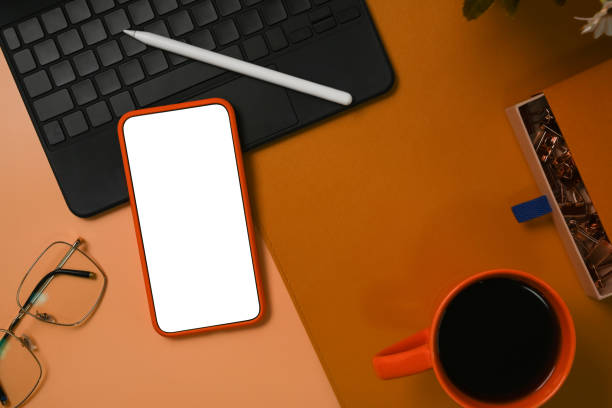 istock Mobile phone with blank screen, laptop computer, glasses and coffee cup on stylish workspace. 1340842826