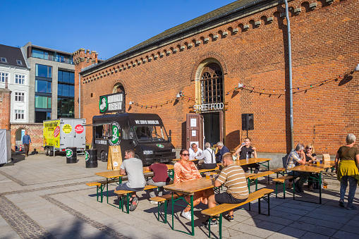 People enjoying the sun at a picknick table during the streetfood festival in Aarhus, Denmark
