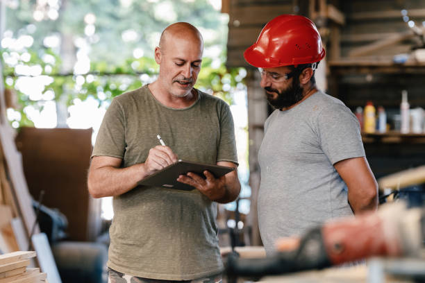 istock Middle Aged Architect Describing His Project To The Carpenter In The Carpentry Workshop 1340848149