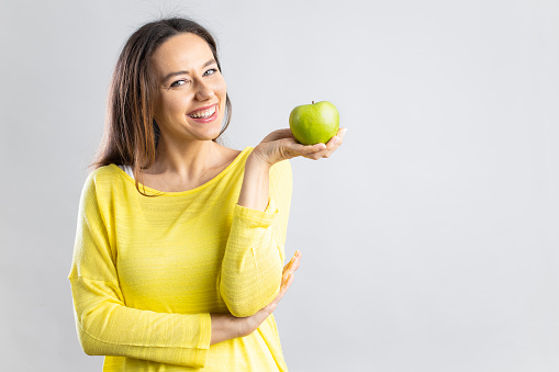 Smiling happy young holding an apple. Healthy nutrition, diet food concept