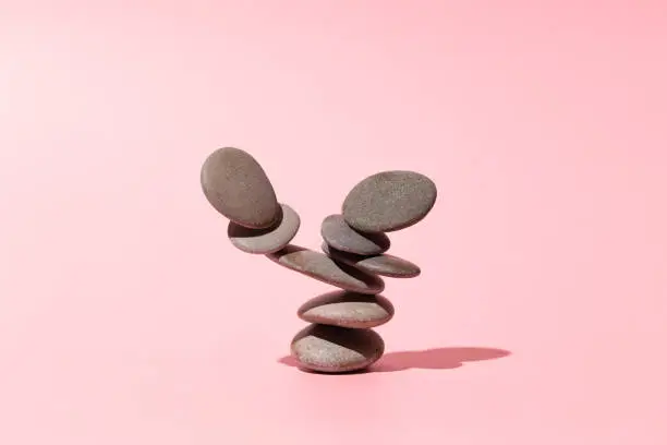 Photo of Concept of balance of gray stones on a pink background