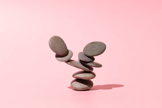 concept of balance of gray stones on a pink background - stack rock imagens e fotografias de stock