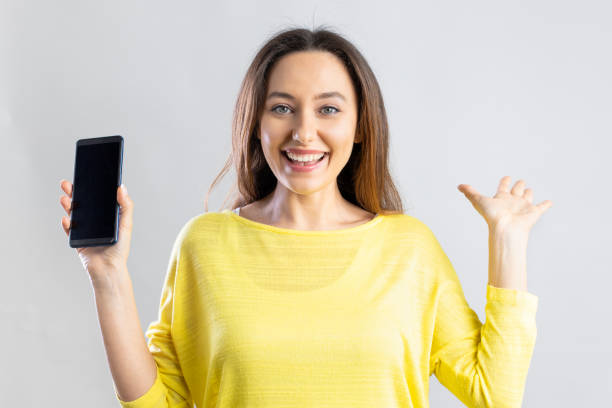 istock Emotional young woman showing blank smartphone screen 1340848737