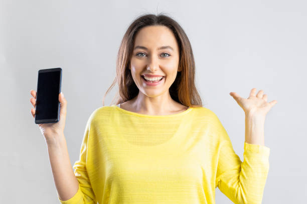 Emotional young woman showing blank smartphone screen
