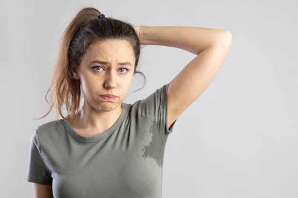 junge frau mit erhobenem arm und achselschweiß - facial expression unpleasant smell shirt caucasian stock-fotos und bilder