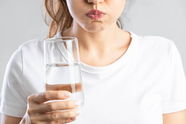 Young woman gargling with a glass of water stock photo