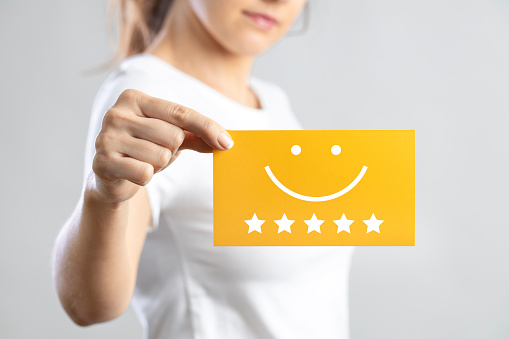 Customer experience concept and business satisfaction survey. Young woman holding yellow card with smiley face