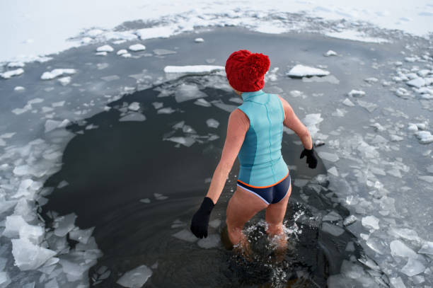 Rear view of active senior woman in swimsuit outdoors in winter, cold therapy concept. Rear view of an active senior woman in swimsuit outdoors in winter, cold therapy concept. woman cold water swimming stock pictures, royalty-free photos & images