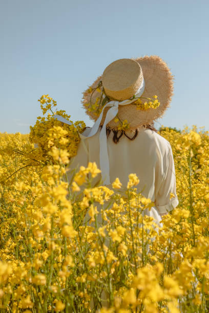 istock woman standing in rapeseed field rear view from behind 1340853039
