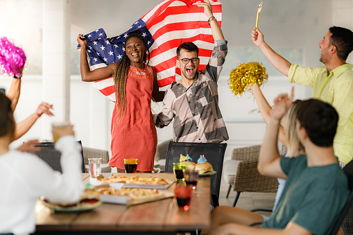 Group of cheerful friends having fun while celebrating National flag day on a patio.