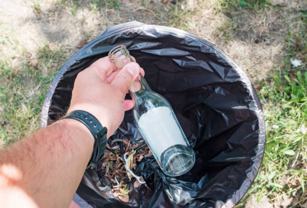 istock Hand putting glass bottle into recycling bin. 1340854660