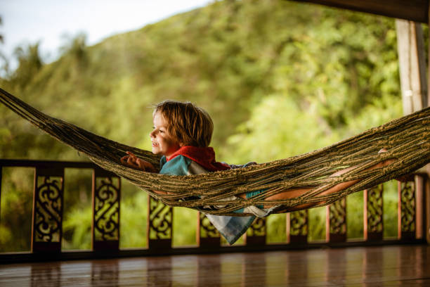 Small happy boy lying in hammock and enjoying on his summer vacation.