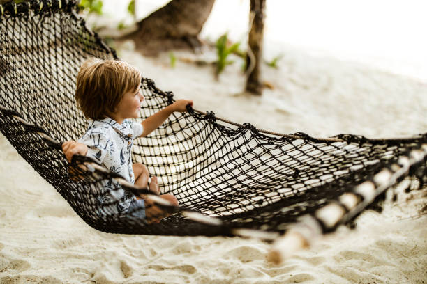 istock Cute boy enjoying while relaxing in hammock on the beach. 1340854843
