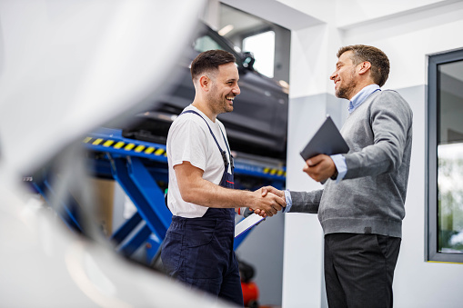 Happy mechanic and his foreman came to an agreement in auto repair shop.