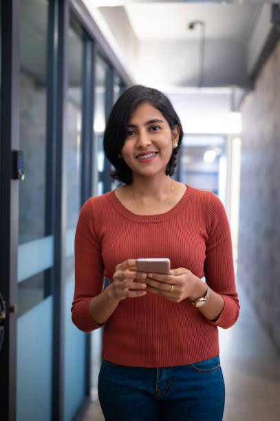 istock Smiling female business executive with smart phone in modern office 1340857002