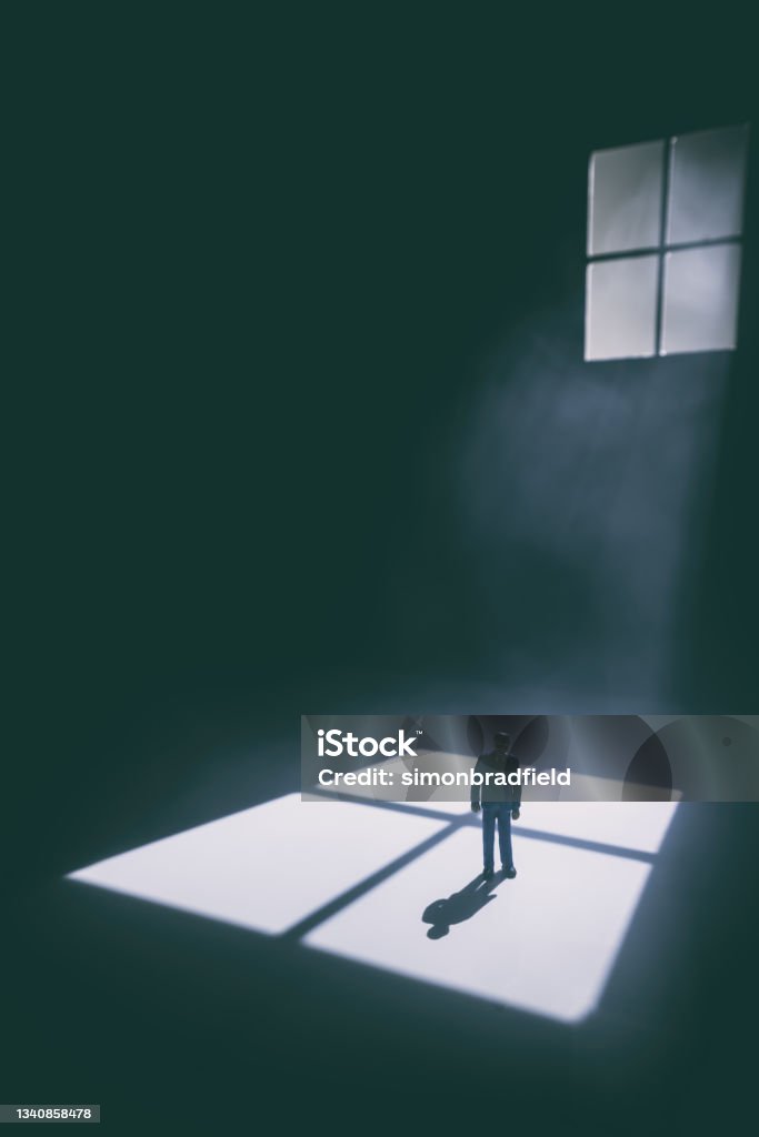 Alone In The Moonlight A man stands in a vast darkened space, illuminated by moonlight streaming through a vast window (miniature photography). Moonlight Stock Photo