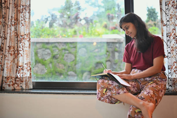 istock Woman writing in a diary sitting at the window 1340863391