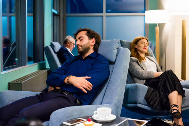 Business people napping in the airport VIP lounge Businessman and businesswoman sitting in armchair in the airport vip lounge and sleeping. People waiting form flight at night. man sleeping chair stock pictures, royalty-free photos & images