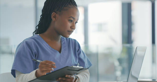 Shot of a female nurse filling in a patients chart stock photo