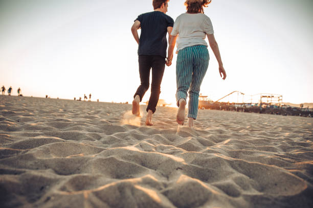 couple profitant du coucher de soleil sur la plage - santa monica beach city of los angeles california photos et images de collection