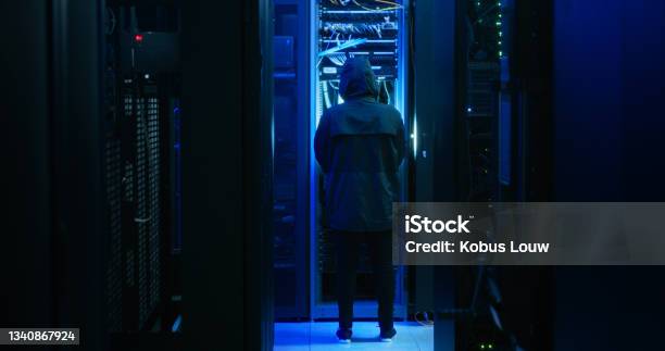 Shot Of A Hacker Walking Through A Server Room Stock Photo - Download Image Now - Criminal, Database, 25-29 Years