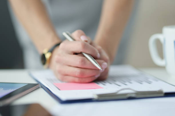 istock Businesswoman holding hands with ballpoint pen over documents with graphs closeup 1340869065