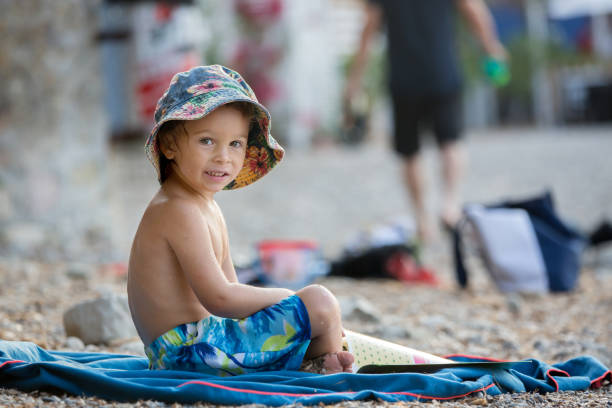 istock Cute blond toddler boy, reading a book on the beach 1340871062