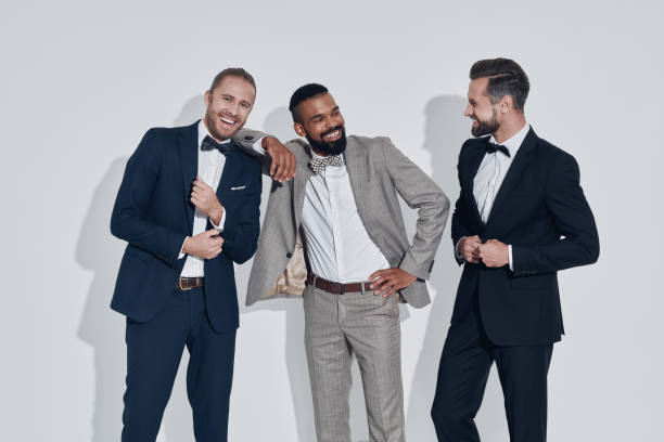 Three handsome young men in suits and bowties looking at camera and smiling