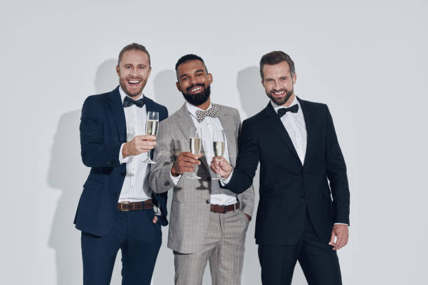 istock Three handsome young men in suits and bowties toasting with champagne 1340871165
