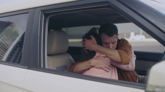 Husband apologizing to sad wife, hugging in the car, family love, forgiveness