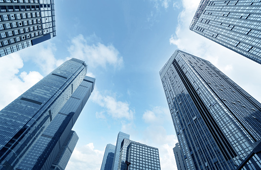 Bottom view of modern skyscrapers in business district against blue sky