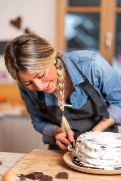 женская выпечка дома: намазывание взбитых сливок на шоколадный бисквит - beauty beautiful braids dairy product стоковые фото и изображения