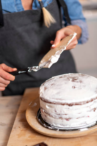 istock Woman baking at home, drip cake preparation: Spreading whipped cream 1340875431