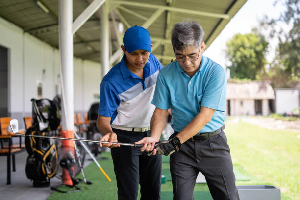 hombre enseñando a un hombre mayor a jugar al golf - golf expertise professional sport men fotografías e imágenes de stock