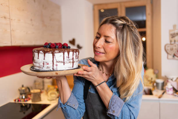 istock Woman baking at home: Proudly showing her chocolate sponge cake with berries 1340877496