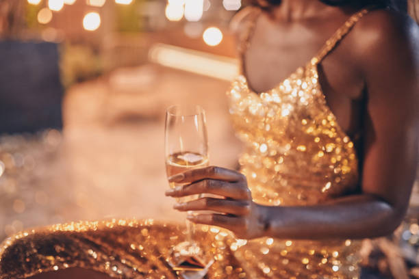 primo piano della bella giovane donna africana in abito da sera che tiene il flauto con champagne - champagne celebration glass black foto e immagini stock
