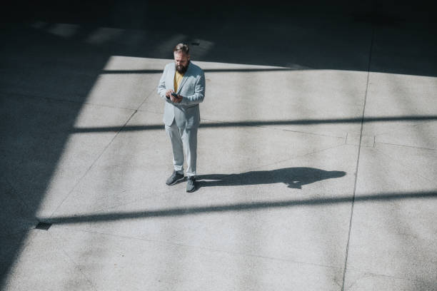 istock overhead view on senior business man standing at town square tapping on mobile 1340881602