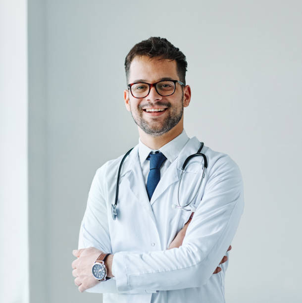 joven médico hospital medicina médica atención médica clínica consultorio retrato gafas hombre estetoscopio especialista - medical occupation uniform surgeon indoors fotografías e imágenes de stock