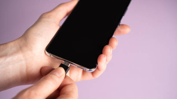 istock Hand plug-in type-c cable into mobile phone to charge. Smartphone battery charging. Fast charge concept. Low battery 1340883524