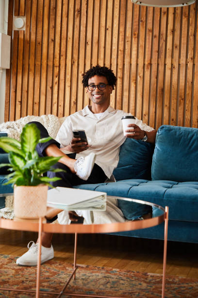 istock Smiling designer drinking coffee and checking his phone during an office break 1340883691