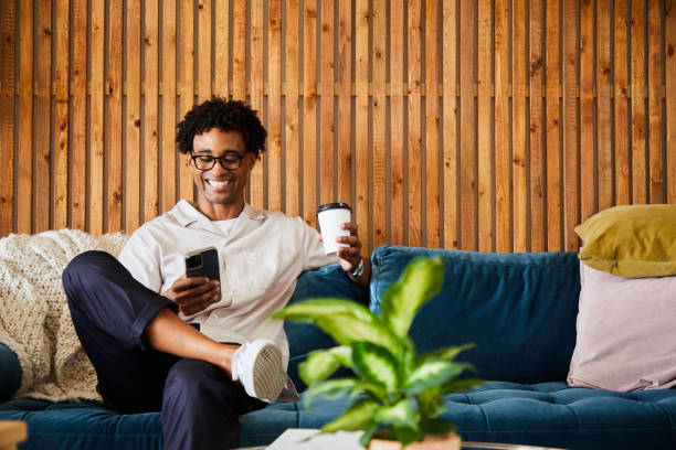 istock Smiling designer drinking coffee and checking his phone during a break 1340884388