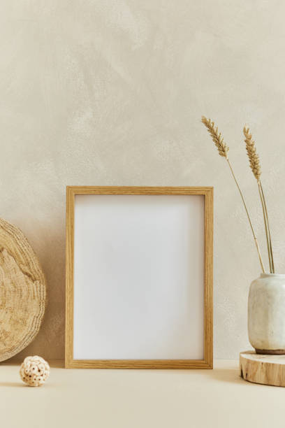 istock Stylish cozy minimalistic interior design composition with mock up poster frame, natural materials as wood and marble, dry plants and personal accessories. Neutral beige colors, template. 1340884632