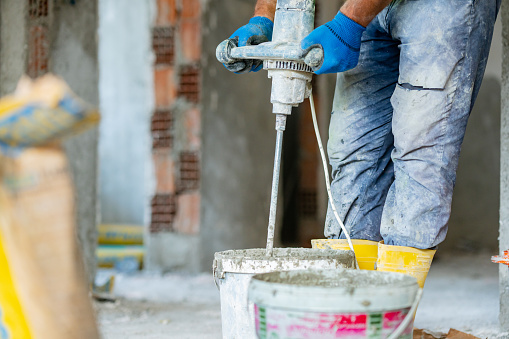 A construction worker is mixing grout.