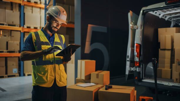 istock Outside of Logistics Retail Warehouse: Handsome Latin Manager Using Tablet Computer for Inventory. Delivery Service with Cardboard Boxes, Online Orders, E-Commerce. Evening Shot 1340887529