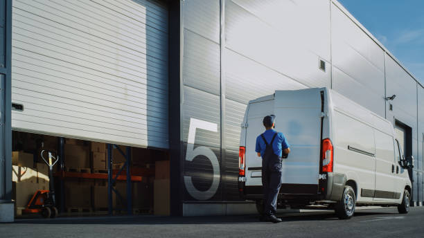 istock Outside of Logistics Distributions Warehouse Worker Loading Delivery Truck with Cardboard Boxes. Online Orders, Purchases, E-Commerce Goods. 1340887536